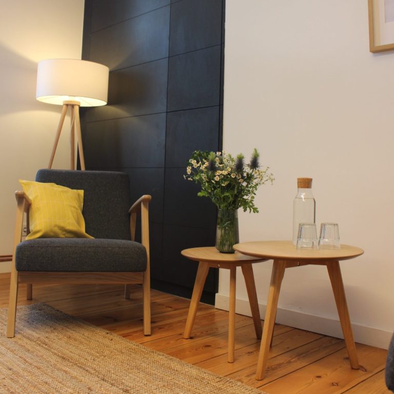 Therapie-Sitzecke unserer Praxis Gemütliche Sitzecke mit zwei Stühlen, Tisch und einer Vase mit Blumen