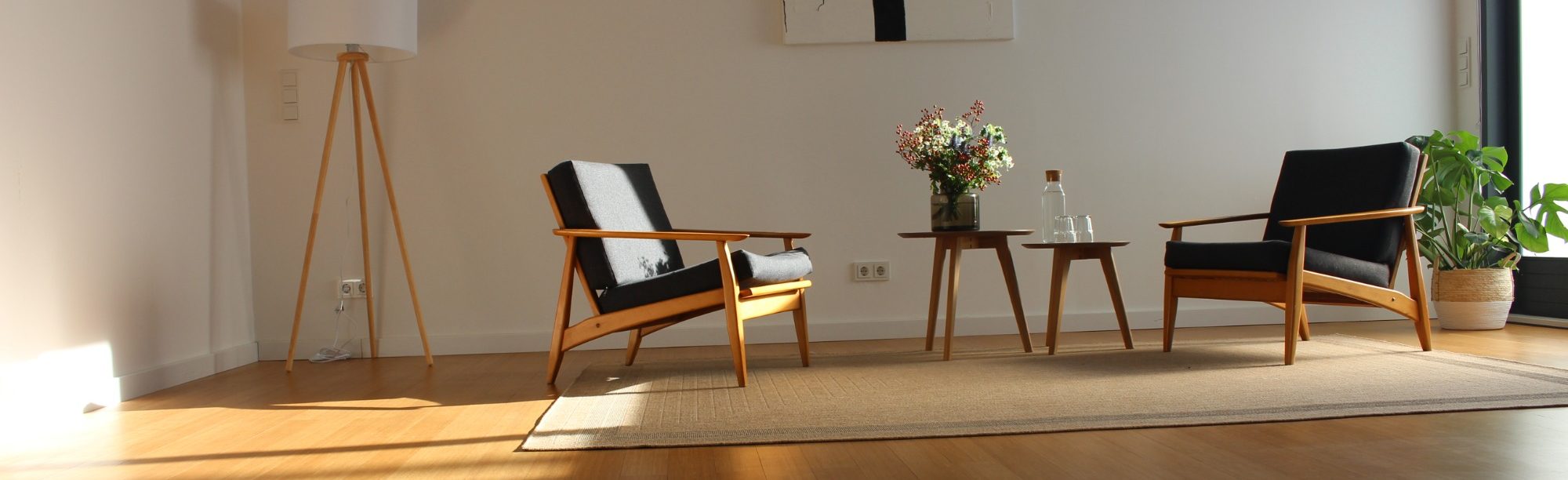 Freundlicher, moderner Therapieraum mit zwei Stühlen, Tisch und Blumenstrauß in einem lichtdurchfluteten Raum